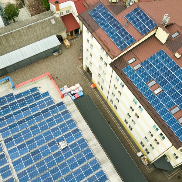 Aerial view of solar power plant with blue photovoltaic panels mounted of industrial building roof.