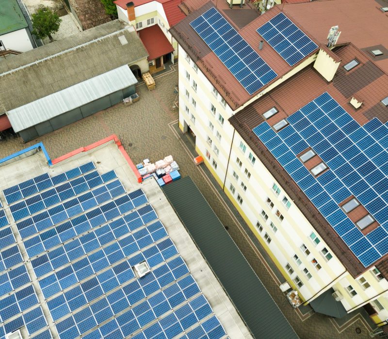 Aerial view of solar power plant with blue photovoltaic panels mounted of industrial building roof.